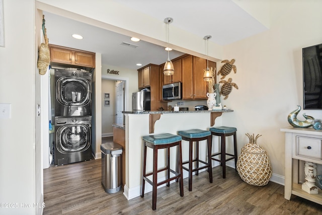 886 New River Inlet Rd Unit 41, North Topsail Beach, NC 28460 - kitchen featuring stacked washer / drying machine, appliances with stainless steel finishes, brown cabinetry, dark stone counters, and recessed lighting