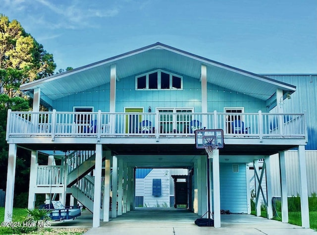 back of property featuring a carport, concrete driveway, stairway, and a deck