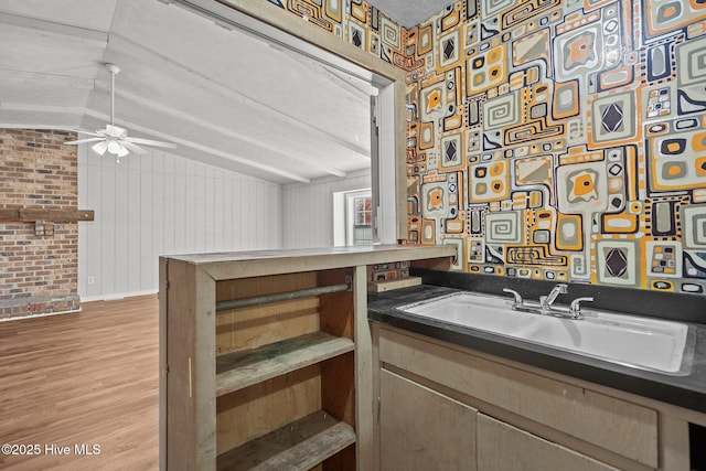 bar featuring lofted ceiling, ceiling fan, light wood-style flooring, a sink, and baseboards