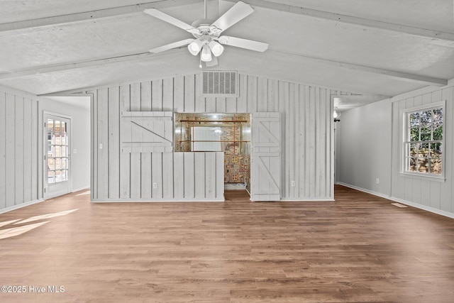 unfurnished living room featuring visible vents, lofted ceiling with beams, baseboards, and wood finished floors