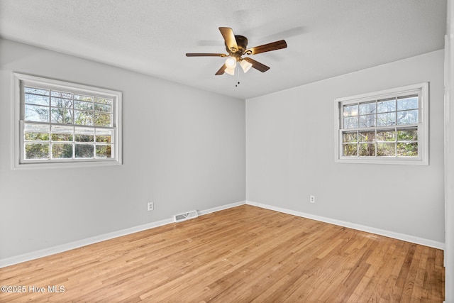 empty room with plenty of natural light, visible vents, light wood-style flooring, and baseboards