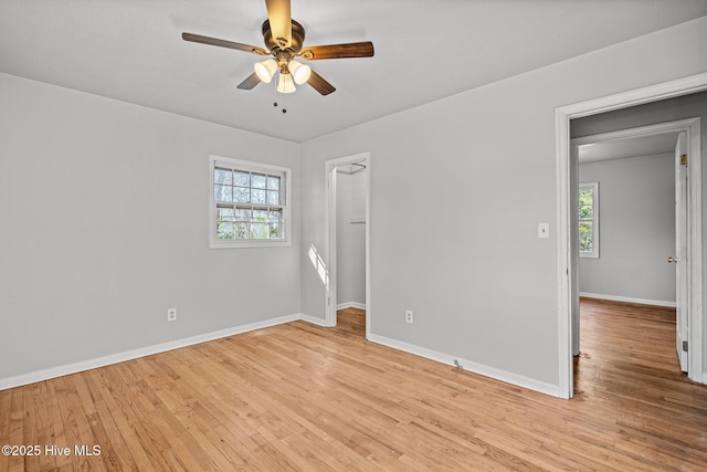 unfurnished bedroom with baseboards, multiple windows, and light wood finished floors