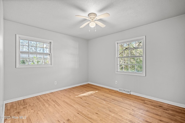 spare room featuring a textured ceiling, wood finished floors, visible vents, and baseboards