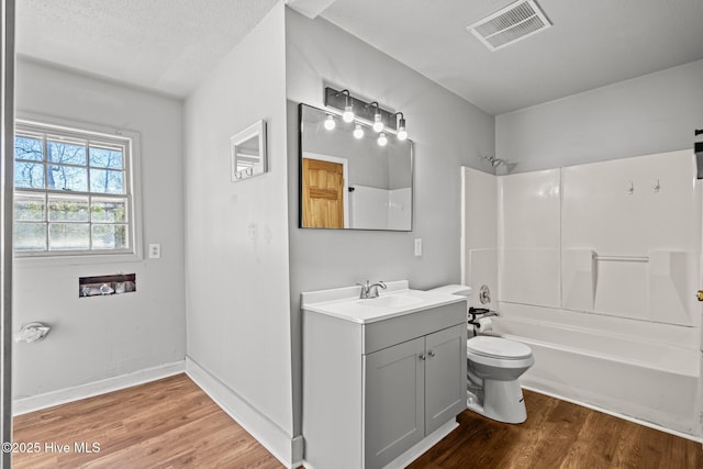 bathroom with visible vents, toilet, vanity, shower / tub combination, and wood finished floors