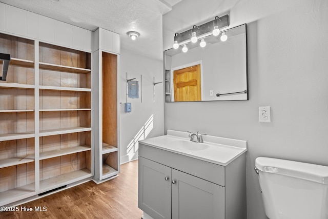 bathroom featuring vanity, a textured ceiling, toilet, and wood finished floors