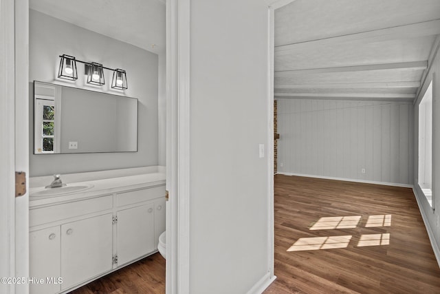 bathroom with toilet, baseboards, wood finished floors, and vanity