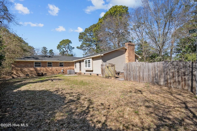 rear view of house with brick siding, a yard, central AC unit, crawl space, and fence