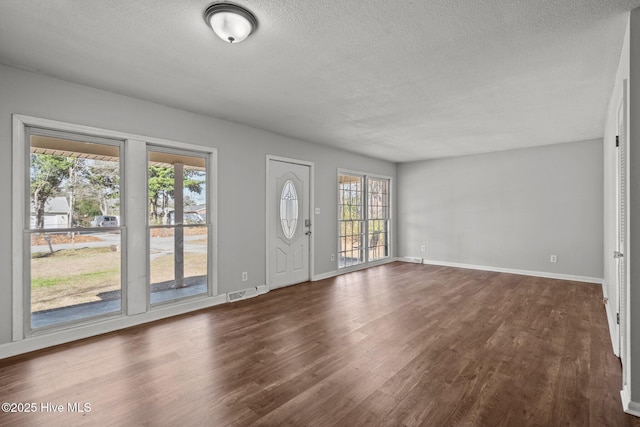 interior space featuring visible vents, baseboards, dark wood finished floors, and a textured ceiling