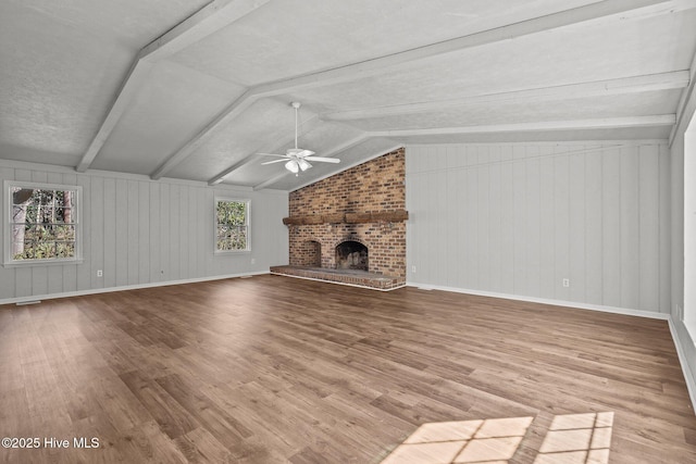 unfurnished living room featuring lofted ceiling, a fireplace, wood finished floors, a ceiling fan, and baseboards