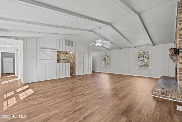 unfurnished living room featuring vaulted ceiling with beams, a fireplace, wood finished floors, visible vents, and a ceiling fan