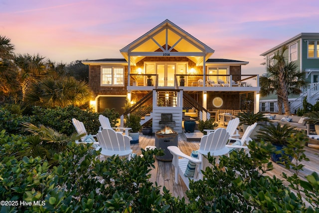 rear view of house with stairway, a wooden deck, a fire pit, and french doors