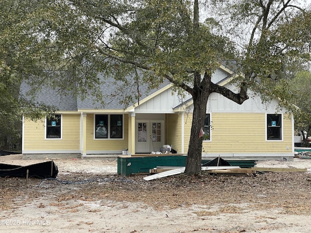 rear view of house featuring board and batten siding and a shingled roof