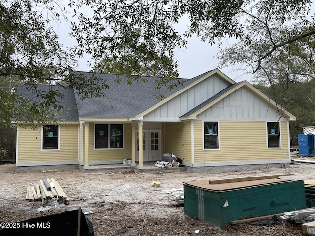 rear view of property with board and batten siding and roof with shingles