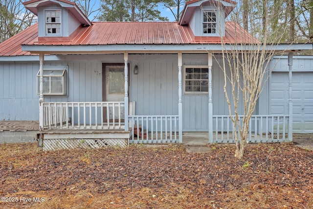 view of front of home with an attached garage, covered porch, and metal roof