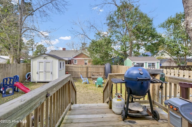 wooden terrace with an outbuilding, area for grilling, a storage unit, and a fenced backyard