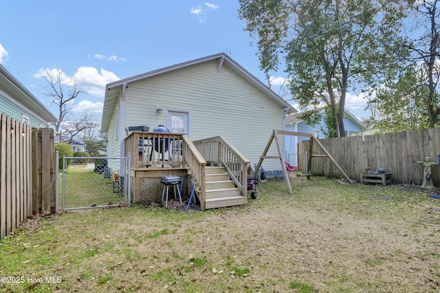 back of house featuring a gate, a fenced backyard, a lawn, and a wooden deck