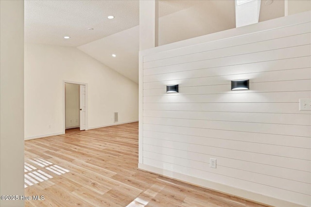 unfurnished room with baseboards, visible vents, lofted ceiling, wood finished floors, and recessed lighting