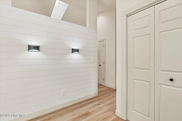 corridor featuring light wood-type flooring and baseboards