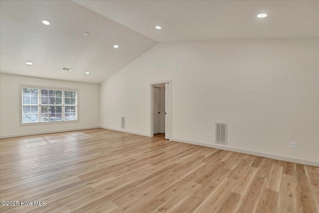 empty room featuring lofted ceiling, visible vents, a textured ceiling, and light wood finished floors