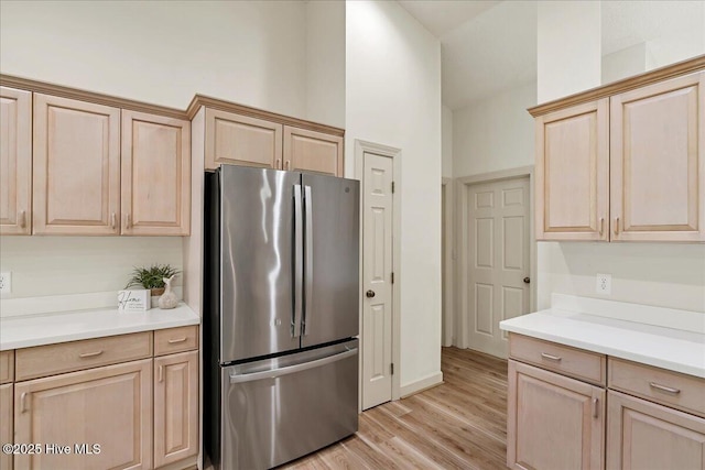 kitchen featuring freestanding refrigerator, light countertops, light wood-style flooring, and light brown cabinetry