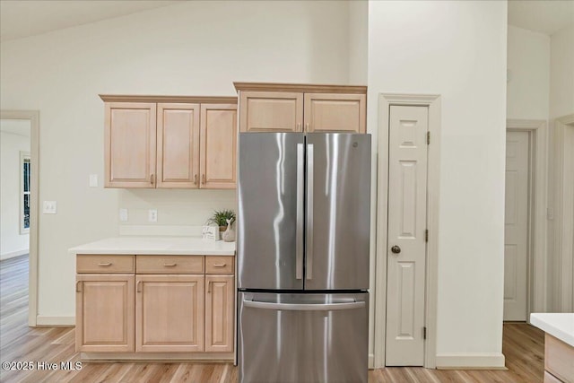 kitchen with light countertops, freestanding refrigerator, light brown cabinets, and light wood-style floors