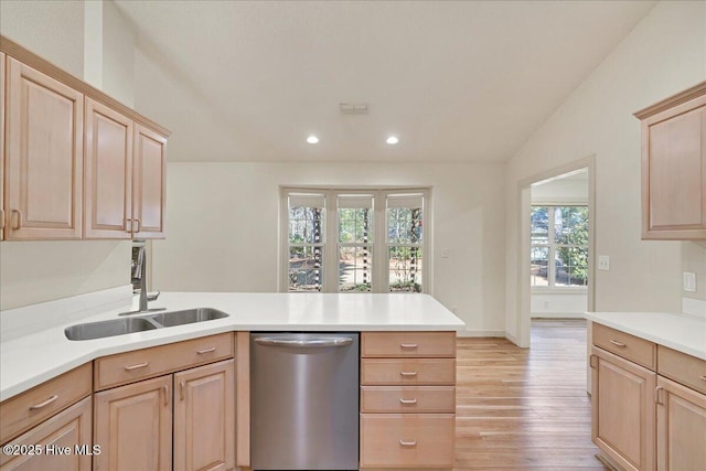 kitchen with a peninsula, a sink, light countertops, dishwasher, and light brown cabinetry