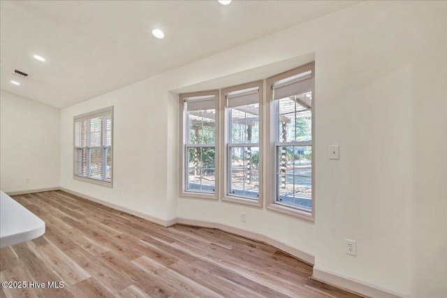 empty room featuring light wood-style flooring, visible vents, baseboards, and recessed lighting