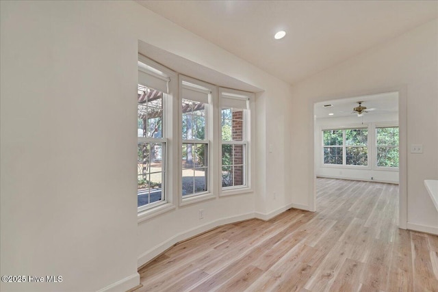 spare room featuring light wood-style floors, lofted ceiling, baseboards, and recessed lighting