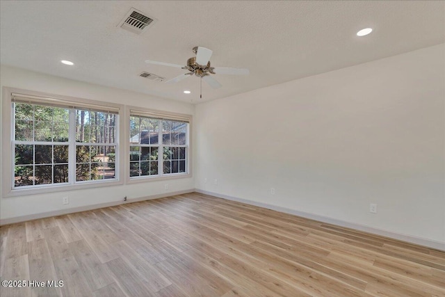 empty room with light wood-style floors, recessed lighting, visible vents, and baseboards