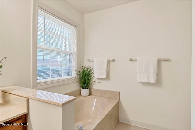 bathroom with baseboards, a garden tub, a textured ceiling, and vanity