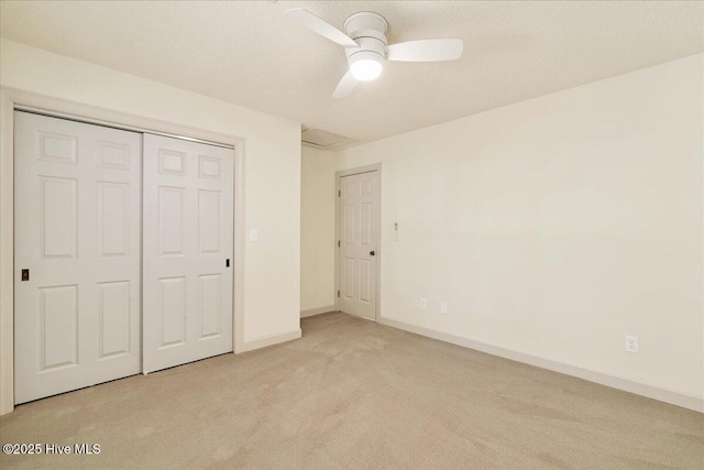 unfurnished bedroom with a closet, light carpet, a textured ceiling, and baseboards