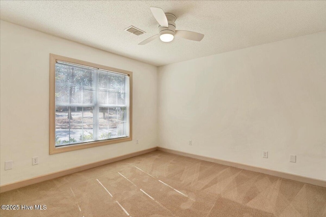 empty room with light colored carpet, visible vents, a textured ceiling, and baseboards