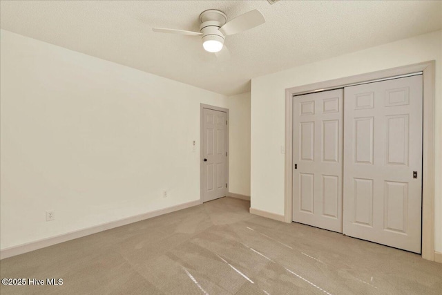 unfurnished bedroom with a textured ceiling, a closet, baseboards, and light colored carpet