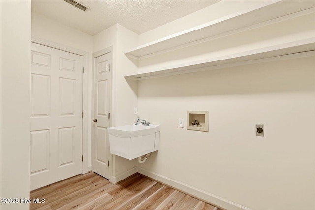 laundry area featuring hookup for a washing machine, hookup for an electric dryer, laundry area, visible vents, and light wood-type flooring