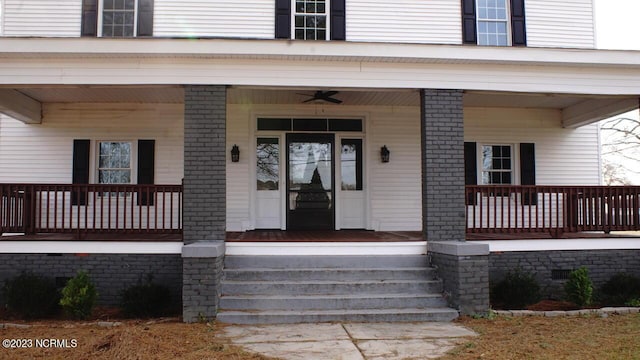 view of exterior entry with a porch, brick siding, and ceiling fan