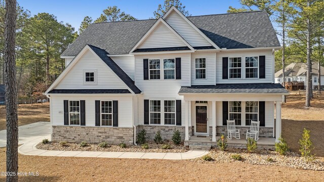 view of front of house with covered porch, stone siding, and a shingled roof