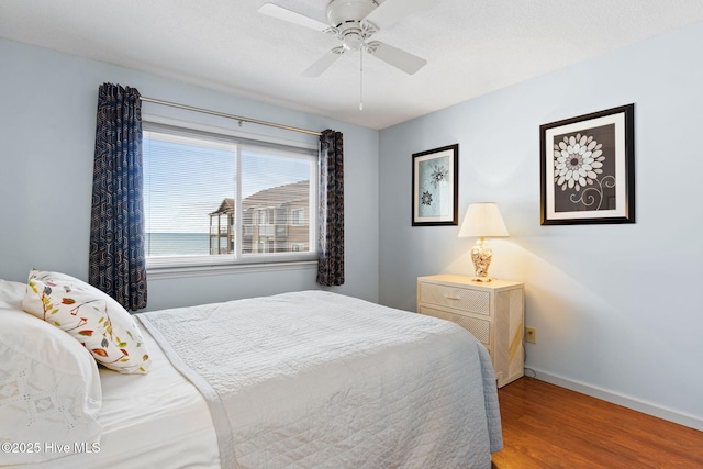 bedroom featuring ceiling fan, baseboards, and wood finished floors