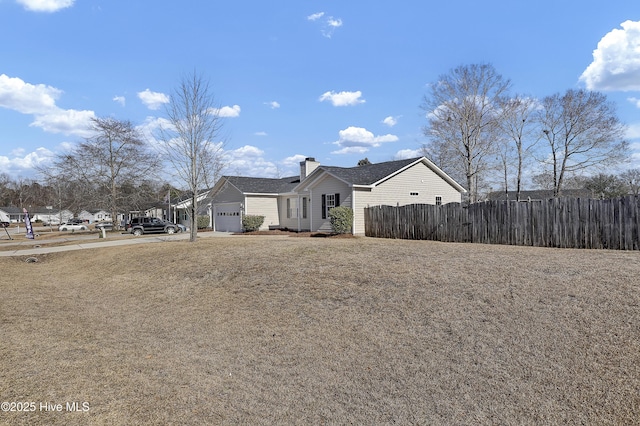 ranch-style house featuring concrete driveway, a chimney, an attached garage, and fence