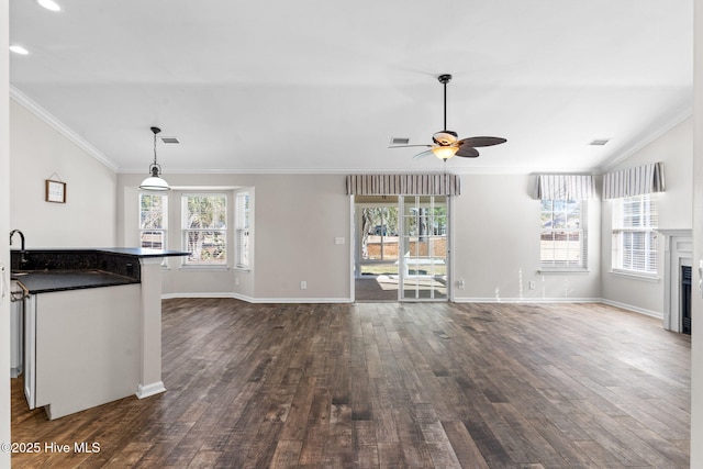 unfurnished living room with a sink, a fireplace, dark wood finished floors, and crown molding