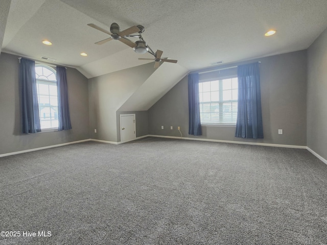 bonus room with vaulted ceiling, carpet flooring, baseboards, and a textured ceiling