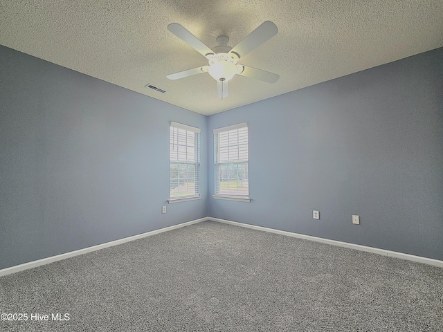 empty room with carpet, visible vents, and baseboards