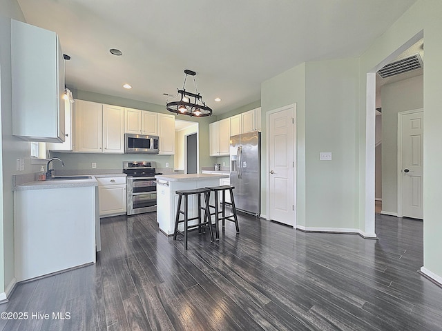 kitchen featuring a sink, a kitchen island, appliances with stainless steel finishes, and white cabinets