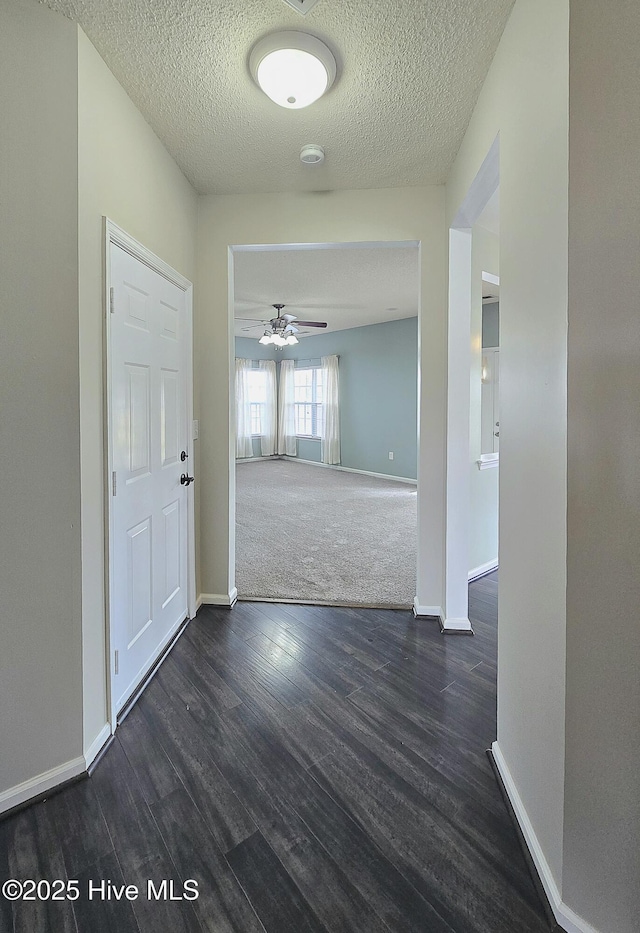 interior space featuring dark wood finished floors, a textured ceiling, and baseboards