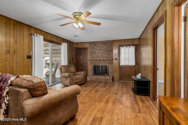 211 Brandon Ave, Tarboro, NC 27886 - living room with ceiling fan, light wood finished floors, wood walls, and a brick fireplace