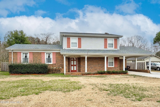 view of front of property with driveway, brick siding, fence, and a front yard