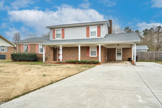 traditional-style home with brick siding, fence, concrete driveway, a chimney, and a front yard