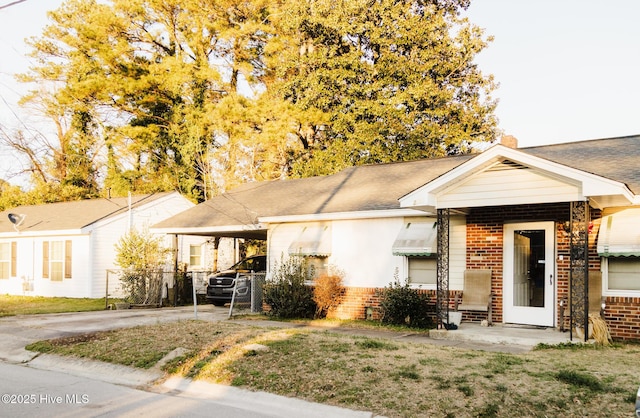 view of front of property featuring concrete driveway, brick siding, fence, and an attached carport