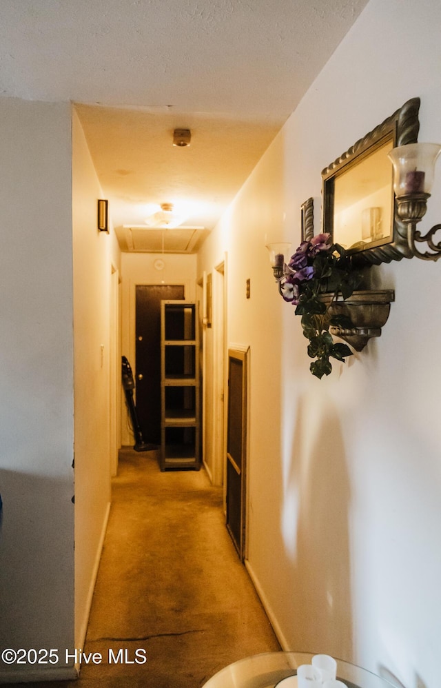 corridor with baseboards, attic access, and light colored carpet