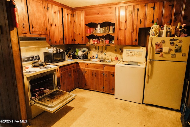 kitchen with black microwave, light countertops, freestanding refrigerator, washer / clothes dryer, and white range with electric cooktop