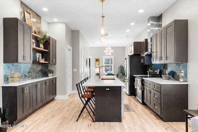 kitchen with a center island with sink, appliances with stainless steel finishes, a breakfast bar, light countertops, and a sink